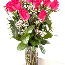 Pink roses arranged in a clear glass vase with small white filler flowers
