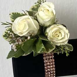 White rose bouquet with green foliage on a black box