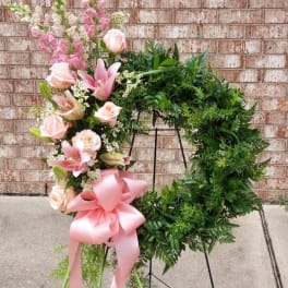 Pink and white floral wreath on a stand with a large pink bow