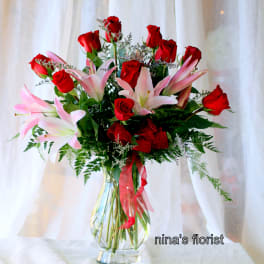 Bouquet of red roses and pink lilies in a clear glass vase