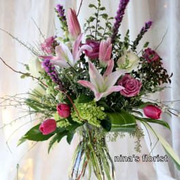 Pink lilies and roses arranged in a clear glass vase
