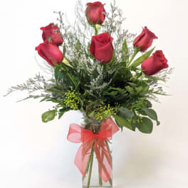 Red roses in a clear glass vase with a red ribbon