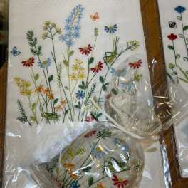 Embroidered floral napkins and a matching heart-shaped pouch in plastic wrap