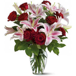 Bouquet of red roses and pink lilies in a clear glass vase