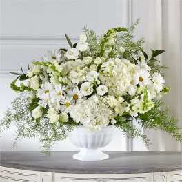 White floral arrangement in a white pedestal vase