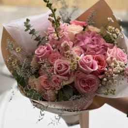 Bouquet of pink roses and small white daisies wrapped in paper