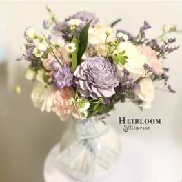 Bouquet of pastel roses and purple flowers tied with a white ribbon