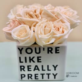 Cream roses in a white square vase with black text