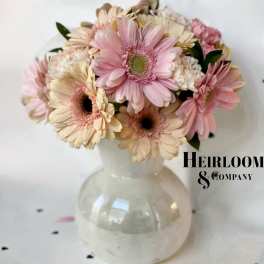 Pink and cream gerbera daisies arranged in a clear glass vase