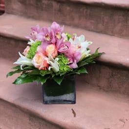 Pink and white floral arrangement in a square glass vase
