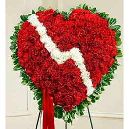 Heart-shaped red floral standing spray with a white diagonal ribbon