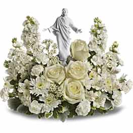 White floral arrangement with a small religious statue in the center