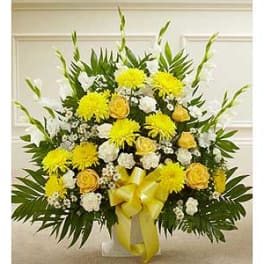 Yellow and white floral arrangement in a clear vase with a yellow ribbon