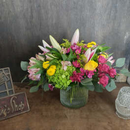 Mixed bouquet in a ribbed glass vase with pink, yellow, and white flowers