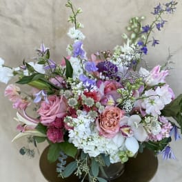 Mixed pink, white, and purple floral arrangement in a vase