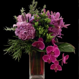 Pink and purple floral arrangement in a tall glass vase