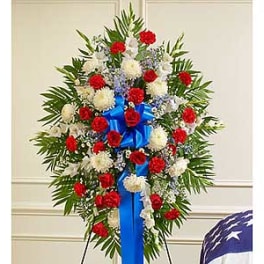 Standing floral spray with red and white flowers and a blue ribbon