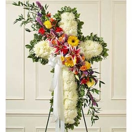 Large standing floral cross with white ribbon and mixed blooms