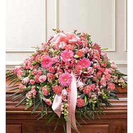 Pink floral casket spray with ribbon on a wooden casket