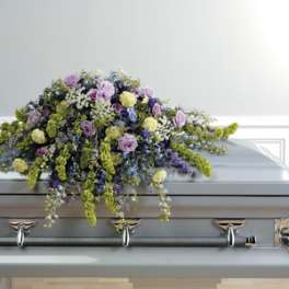 Pastel floral spray arranged on top of a gray casket