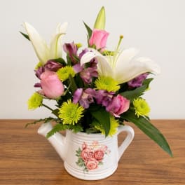 Mixed bouquet in a white watering can with pink, white, and purple flowers