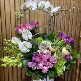 Pink and white floral arrangement in a white vase with orchids and roses