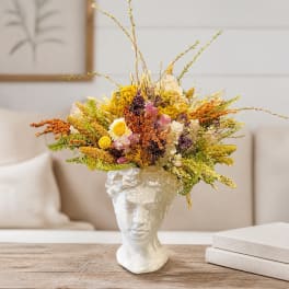 Dried flower arrangement in a white sculpted face vase