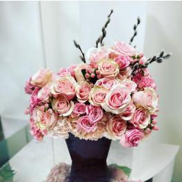 Pink and blush roses arranged in a dark vase