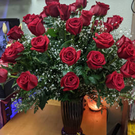 Tall vase arrangement of red roses with baby's breath