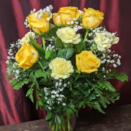 Yellow roses and pale carnations in a glass vase