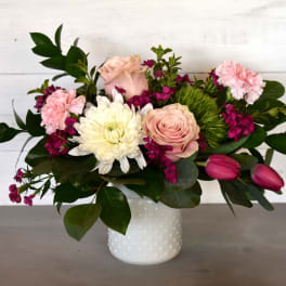 Pink and white flowers arranged in a white vase