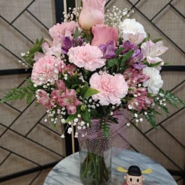 Pink and white bouquet in a glass vase with a small figurine beside it