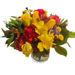 Mixed bouquet of yellow, red, and purple flowers in a glass vase