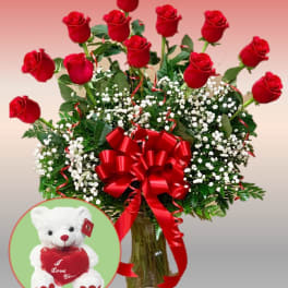 Red roses in a glass vase with baby's breath and a teddy bear inset