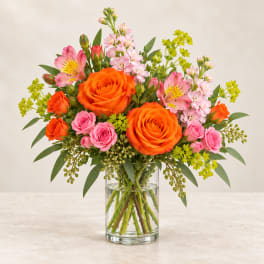 Bouquet of orange and pink flowers in a clear glass vase