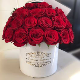 Round white hatbox of red roses with a small card on a white seat