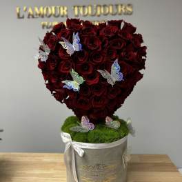 Heart-shaped bouquet of red roses in a gray box with butterfly decorations