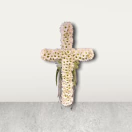 White daisy cross with ribbon accents on a plain wall