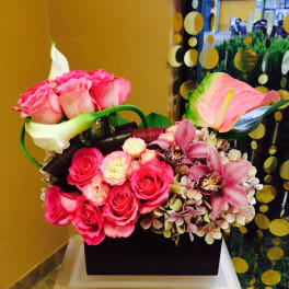 Pink roses and orchids arranged in a black box with white calla lilies