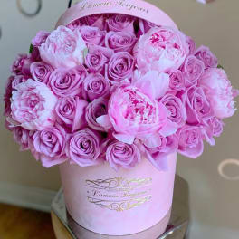 Pink roses and peonies arranged in a round pink hat box