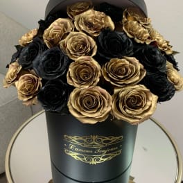 Black and gold roses arranged in a tall black hat box with gold lettering