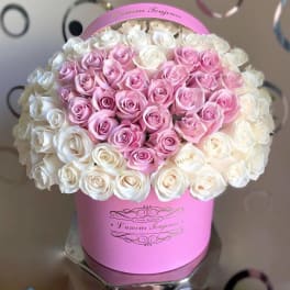 Round pink hatbox filled with tightly packed pink and white roses