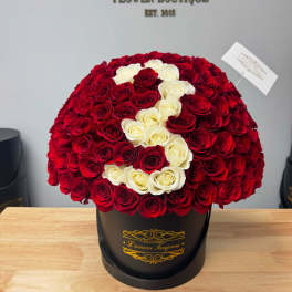 Large red and white rose arrangement in a black hatbox