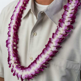 Purple and white orchid lei worn around a person's neck over a light shirt