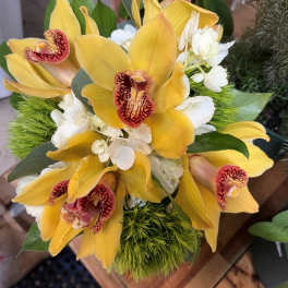 Bouquet of yellow orchids with white flowers and green accents