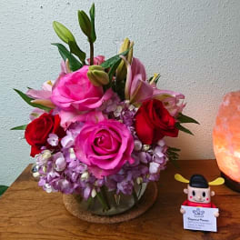 Pink and red roses with lilies in a glass vase