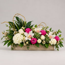 Long floral arrangement with pink and white roses in a wooden box