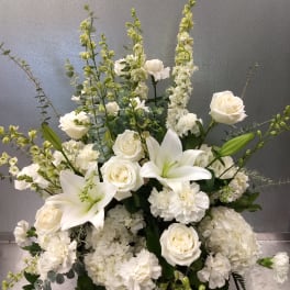 White roses and lilies arranged with tall white blooms in a vase