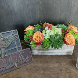 Rectangular floral arrangement with orange roses and succulents in a wooden box