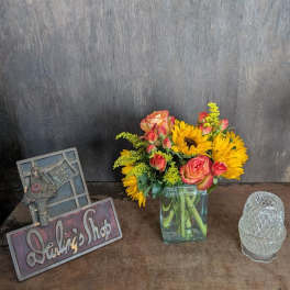 Bouquet of sunflowers and pink roses in a square glass vase